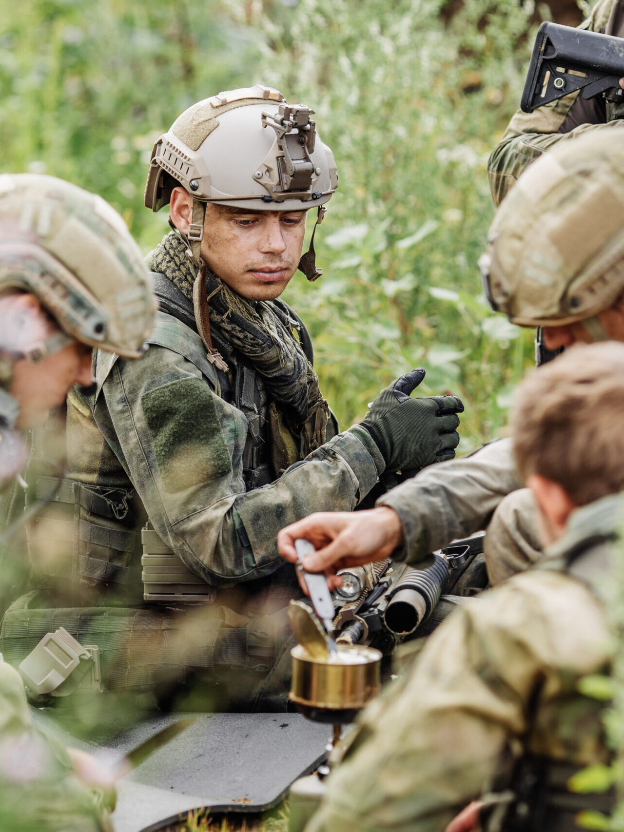 Military personnel gathered in the field while preparing their meal.