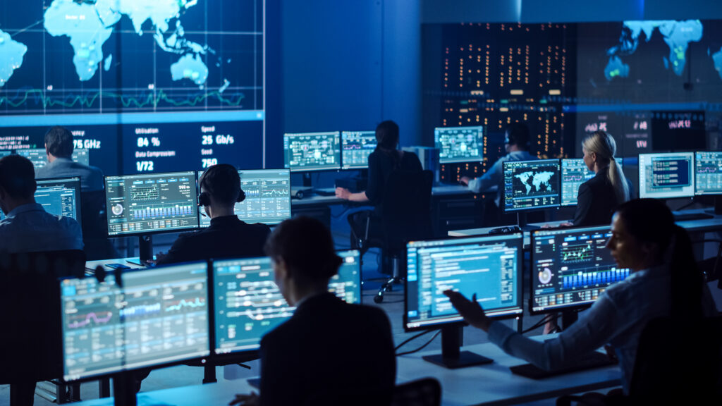 Operations team monitoring multiple screens in a modern command and control center.